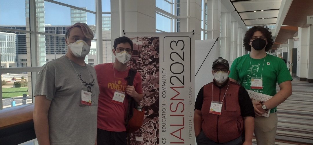 picture of four individuals next to a banner for socialism conference 2024