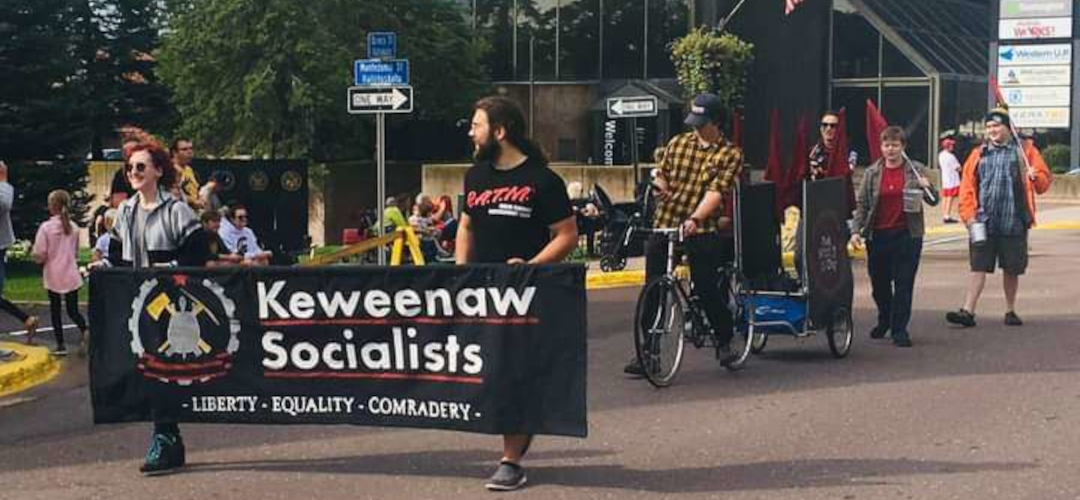 picture of a group of individuals marching with a keweenaw socialists banner